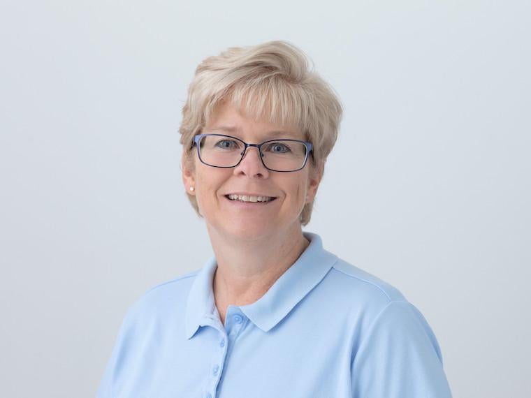 A portrait of a woman wearing a button polo sheet and glasses.