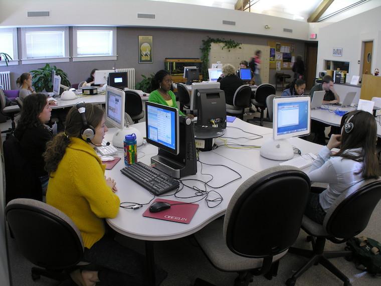 A computer lab with students wearing headphones and working on computers.