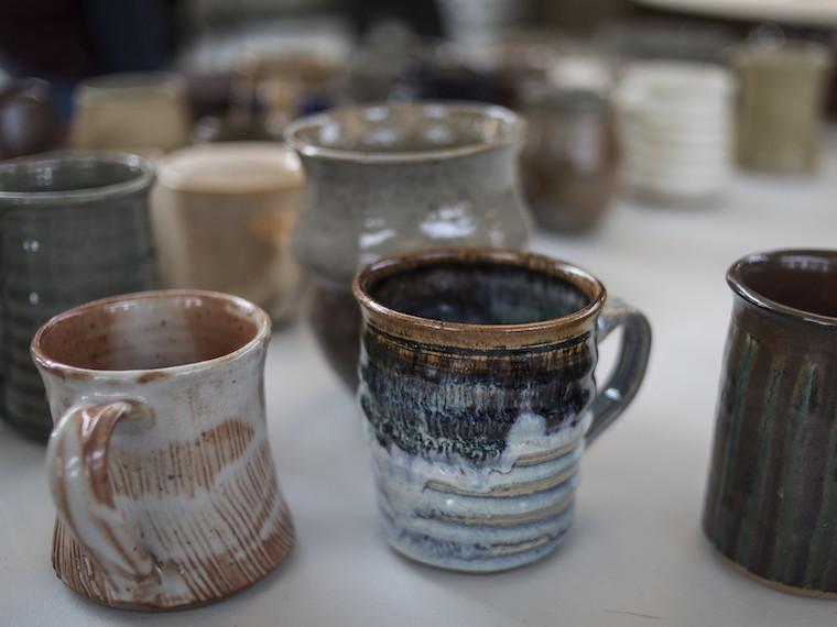 Handmade mugs sit on a table.