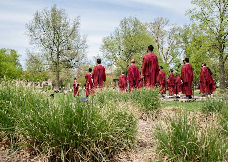 A group of people wearing choir robes stand in a field.