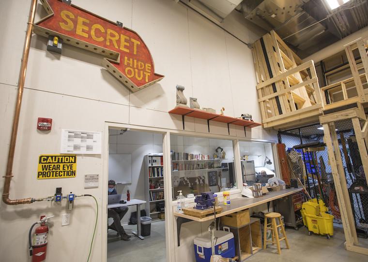 A large sing above a door points to a small office with two people working in it.