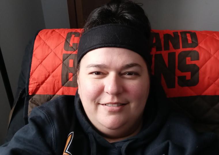 A woman takes a selfie while sitting on a chair.