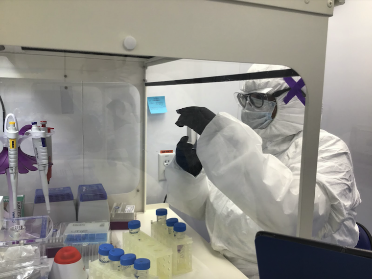 A student wearing a hazmat suit and goggles works in a chemistry lab.