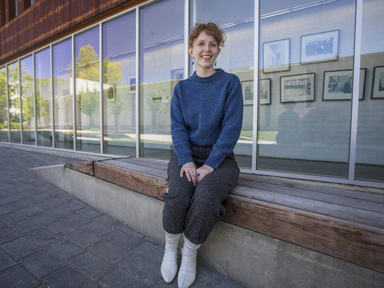 A female student sits on an outdoor bench.