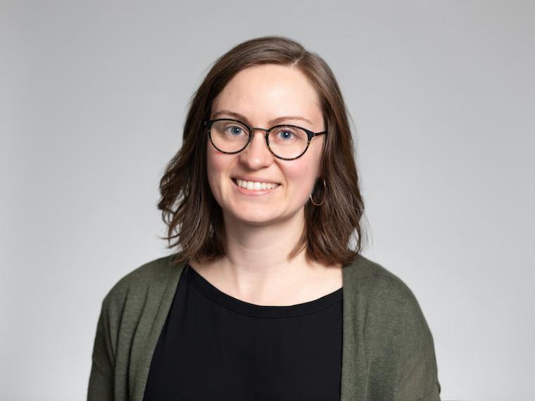 A portrait of a woman wearing a sweater and glasses