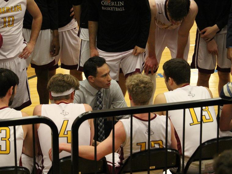 A coach speaks to his players on the sidelines.