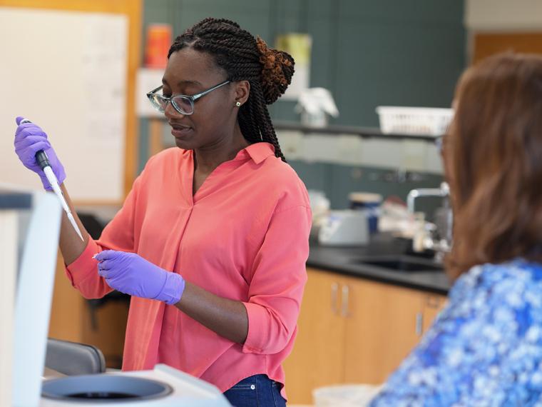 Faythe earing safety gear and holding a large pipet in a science lab