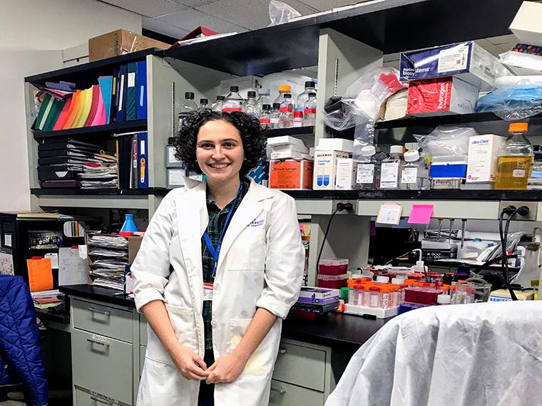 Lisa Learman, wearing a lab coat, stands in a science lab.