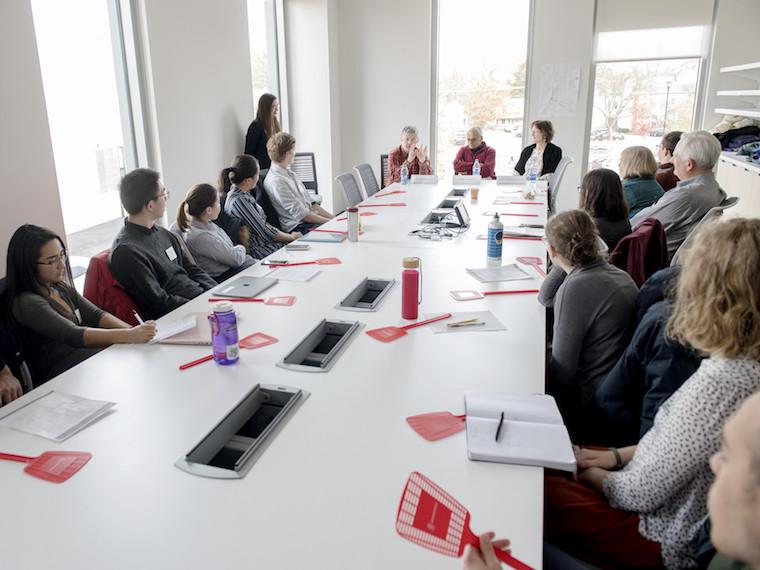 Students sit at a long conference room table.