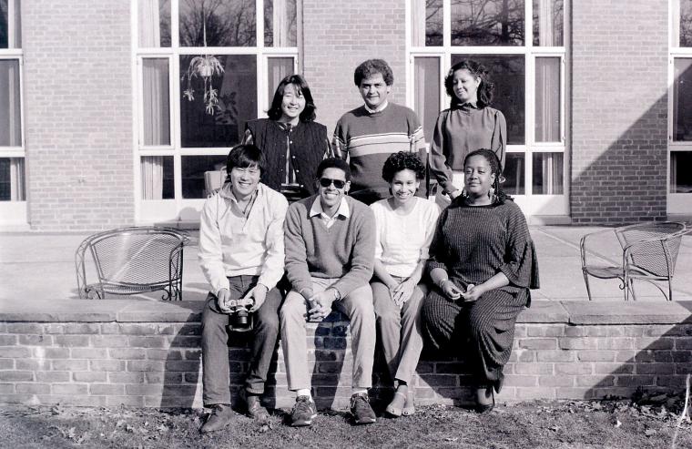 Seven people pose together outside a campus building.