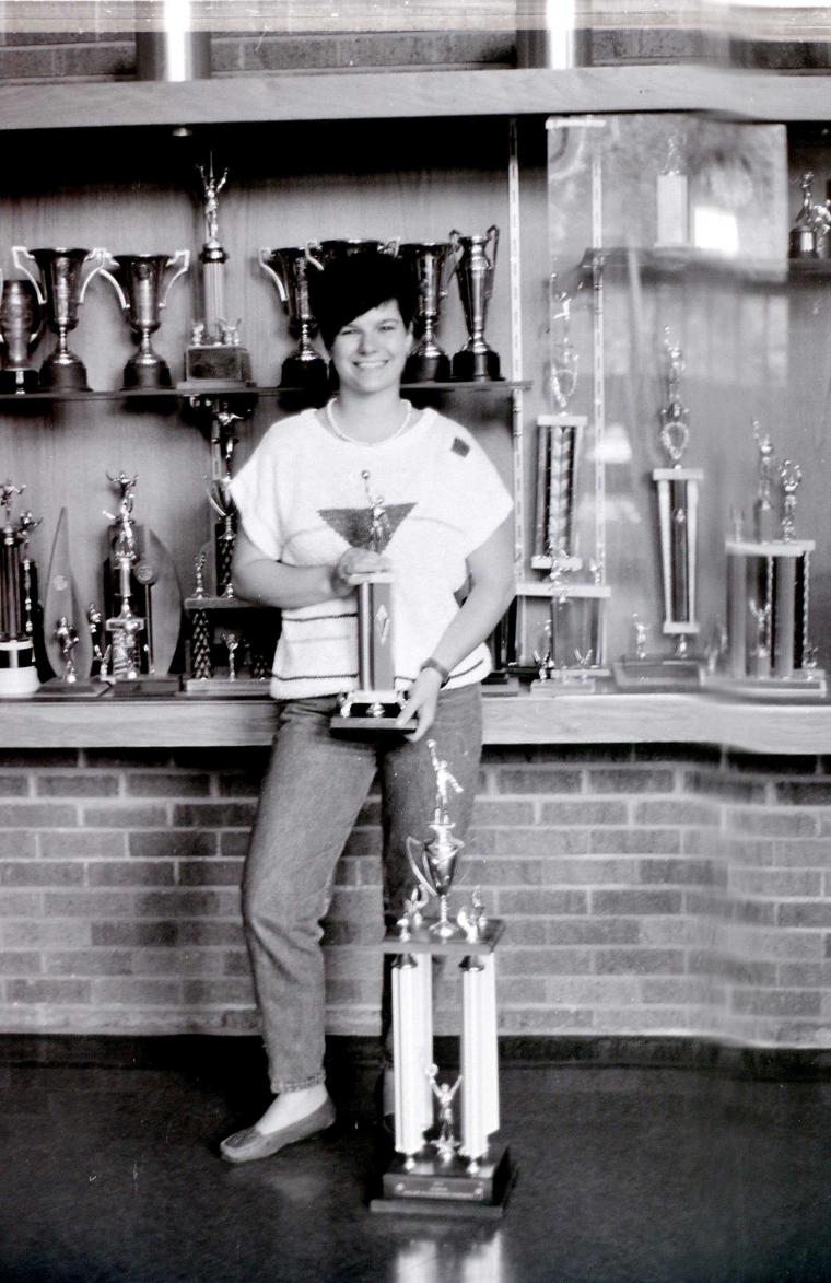 Female student athlete posing with trophies.