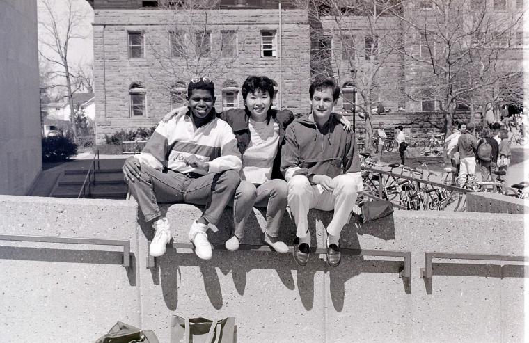 Three students seated on a railing outside Mudd Center.