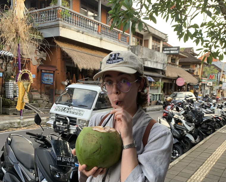 Ilana sips on a fresh coconut in the middle of a city
