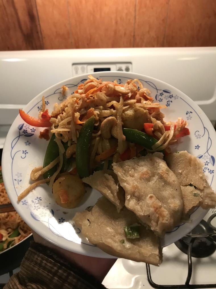 plate of noodle stir-fry and scallion pancakes above a stovetop