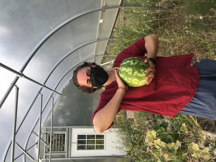 my housemate piper holding a watermelon in a greenhouse