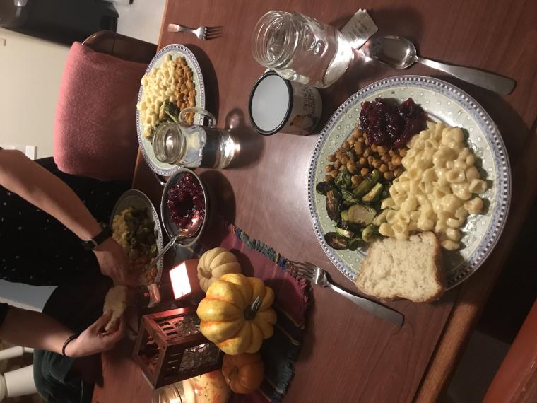 Thanksgiving table with plates of food, candles, and mini decorative pumpkins 
