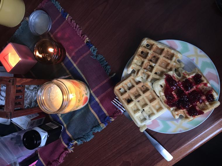 table with a plate of waffles and candles on it