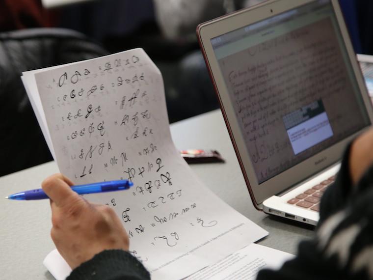 A student holds up a piece of paper with symbols on it.