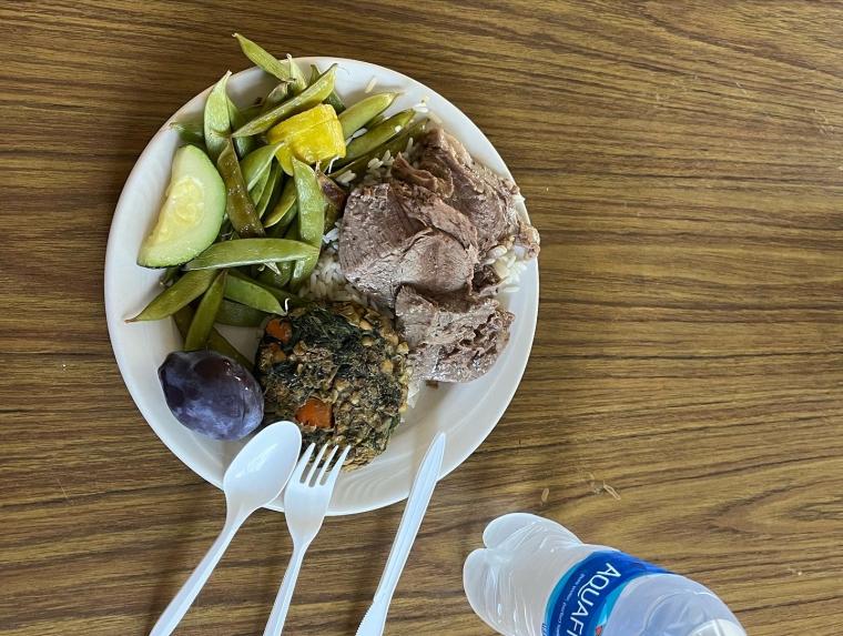 A plate with a vegetable rich meal from Clarity on it, next to a water bottle, on a table.