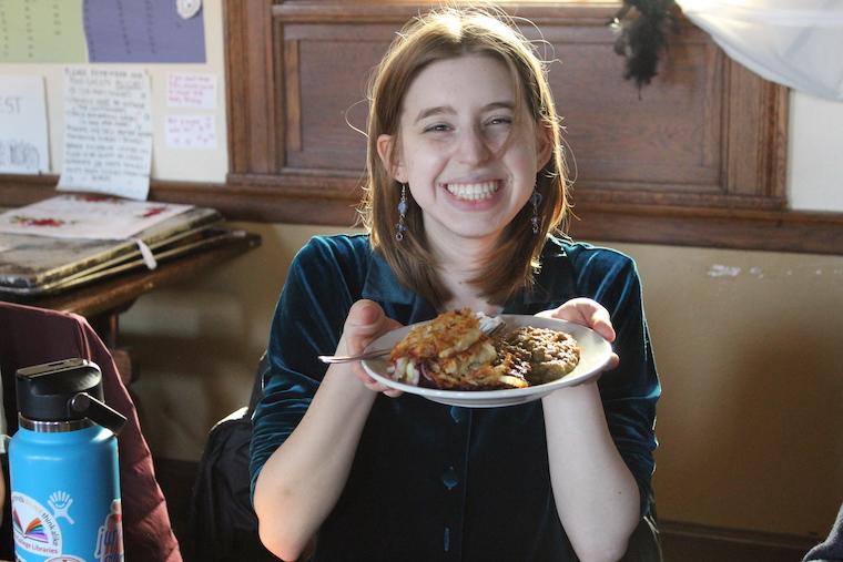 a student smiles while holding a plate of latkes