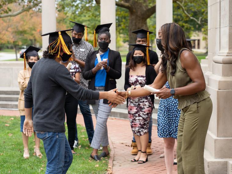 A woman shakes a student's hand.