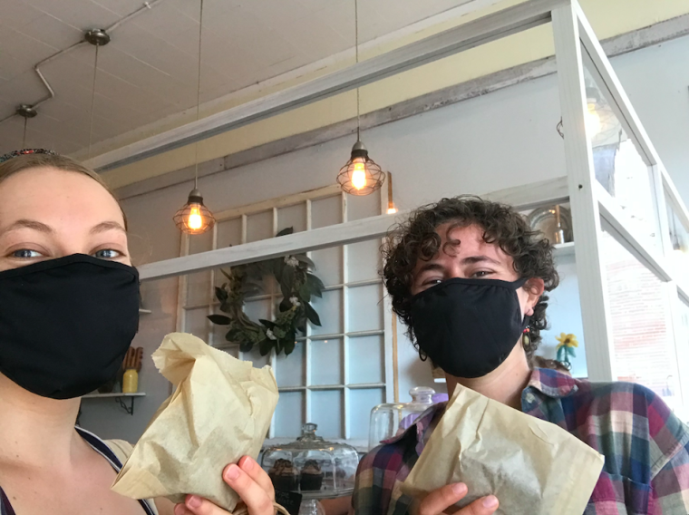 Ruth and Piper wearing masks, holding brownies in the local bakery
