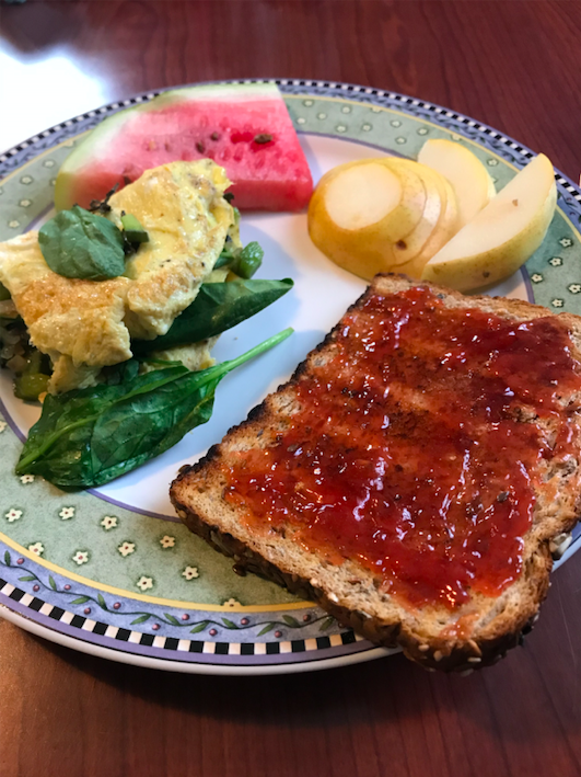 plate of food with toast and jam, omelette, sliced pears, and watermelon