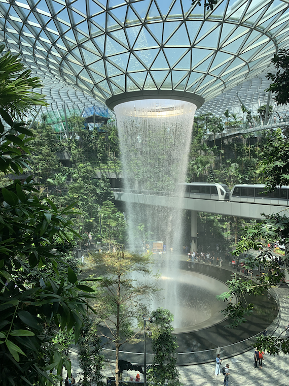 a glass building with greenery gives way to a huge waterfall