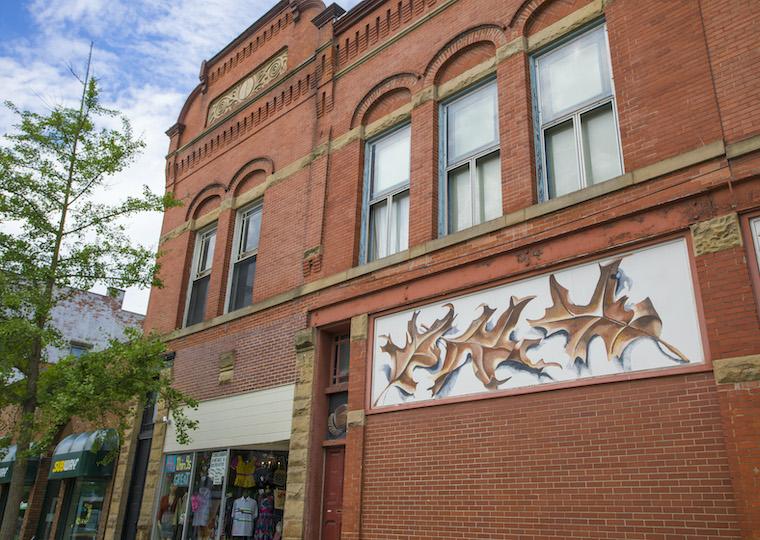 A brick building with a mural of oak leaves on it