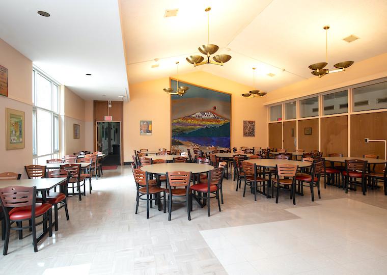 An empty dining hall with a large mural of a mountain on the far wall.